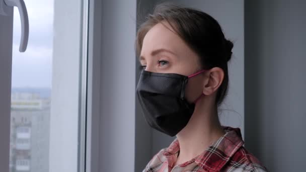 Slow motion: pensive woman wearing medical face mask and looking out of window - Footage, Video
