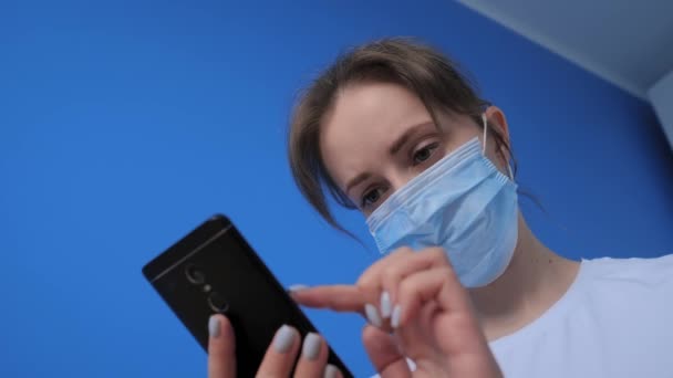 Portret kobiety noszącej medyczną maskę na twarz i korzystającej ze smartfona - slow motion - Materiał filmowy, wideo