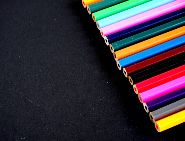 Colored pencils on a black textured background. Suitable for advertising background. Suitable for mockups - Фото, изображение