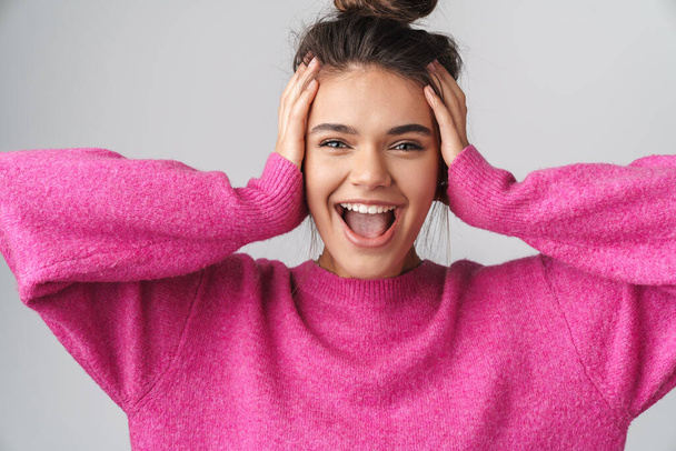 Image of nice excited woman in pink sweater smiling and grabbing her head isolated over white background - Photo, image