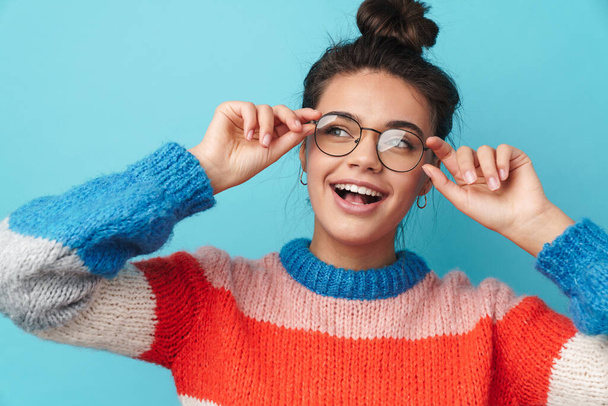 Image of excited beautiful woman holding eyeglasses and smiling isolated over blue background - Photo, Image