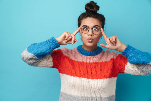 Image of amusing young woman holding eyeglasses and grimacing isolated over blue background - Foto, imagen