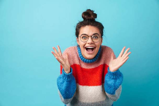Image of happy beautiful woman in eyeglasses smiling and expressing surprise isolated over blue background - Foto, Bild