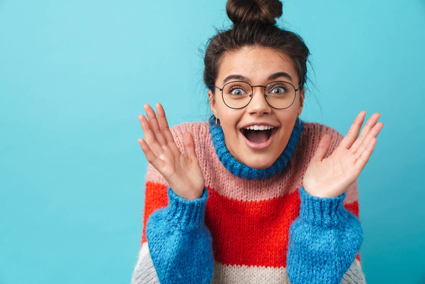 Image of happy beautiful woman in eyeglasses smiling and expressing surprise isolated over blue background - Фото, зображення