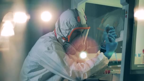 Pracownik w kombinezonie robi testy w laboratorium podczas pandemii koronawirusowej.. - Materiał filmowy, wideo