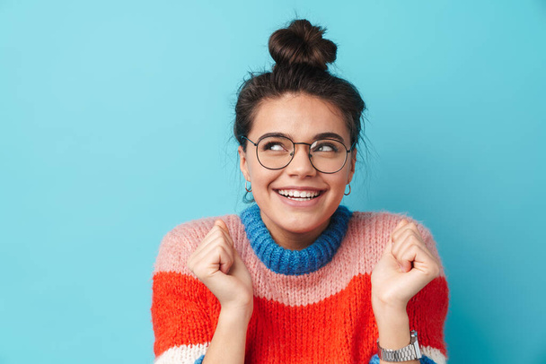 Image of happy beautiful woman in eyeglasses smiling and looking upward isolated over blue background - Fotó, kép