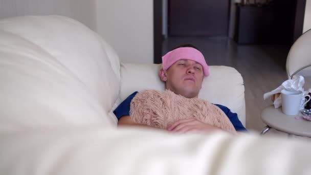 Ein Mann wird krank, liegt mit starken Kopfschmerzen auf dem Sofa - Filmmaterial, Video