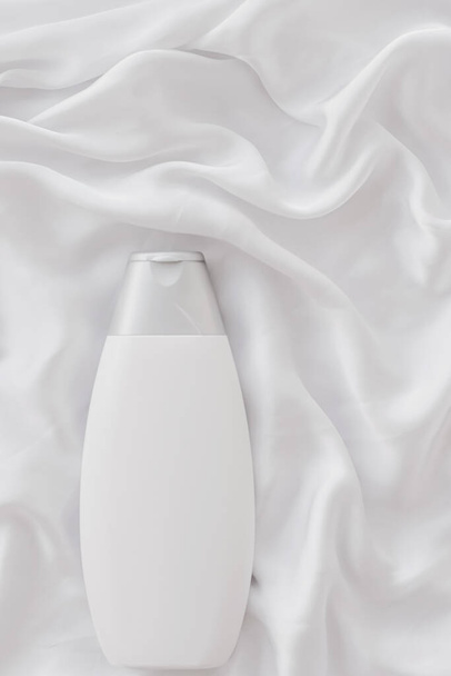 Blanco etiket cosmetische container fles als product mockup op witte zijde achtergrond - Foto, afbeelding
