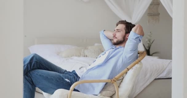 Perezoso relajado joven hombre que se enfría en silla cómoda en casa
 - Metraje, vídeo