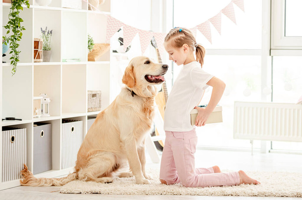 Little girl presenting gift to dog - 写真・画像