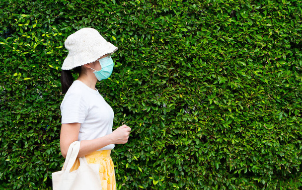 giovane donna asiatica che indossa maschera chirurgica prima di andare a fare shopping per prevenire l'infezione covid-19 o coronavirus e pm 2.5. nuovo stile di vita normale
 - Foto, immagini