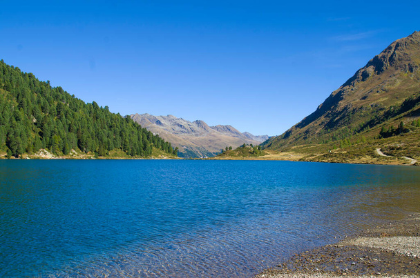 青空の下緑の森や花崗岩の石や雪の上に輝く青い山の湖 - 写真・画像