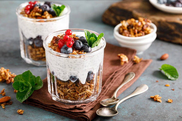 Layered blueberry and red currant parfait with chia yogurt, homemade oat granola and fresh berries for breakfast - Zdjęcie, obraz
