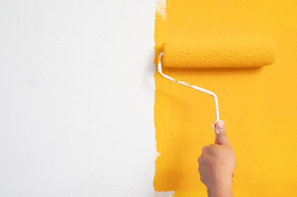 De monteur schildert geel op de muur.. - Foto, afbeelding