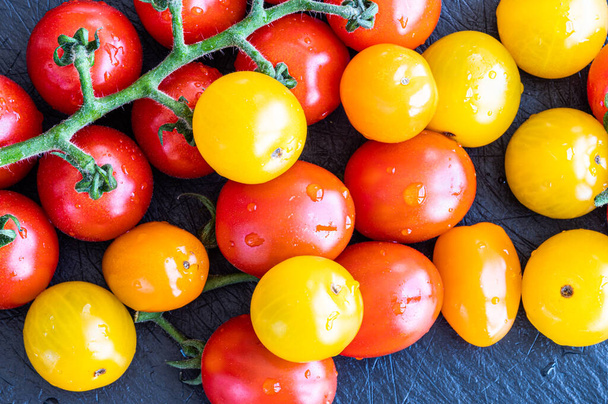 Свежие красные и желтые помидоры черри над черной доской
 - Фото, изображение