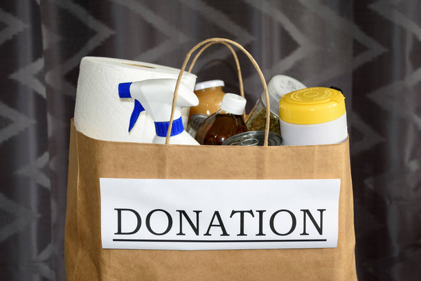 チャリティーと援助の概念:コヴィッド-19/コロナウイルス流行中に寄付するための食品や掃除用品を含む「寄付」という言葉で袋/箱の閉鎖 - 写真・画像