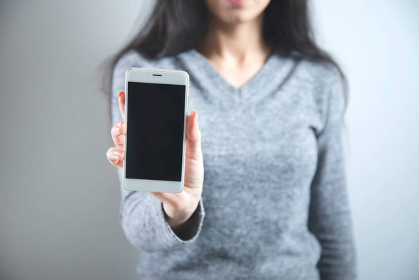 woman hand holding smart phone on grey background - Zdjęcie, obraz