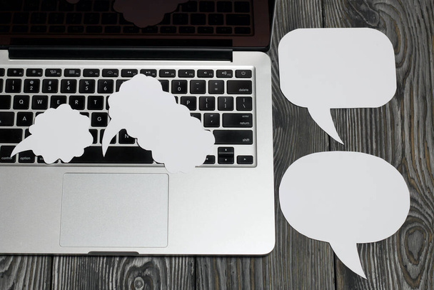 Speech bubbles on a background of brushed pine boards. The edge of the bloggers laptop is visible - Fotoğraf, Görsel