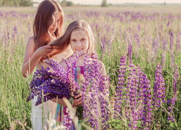 Two adorable girl with flowers outdoor - Foto, imagen