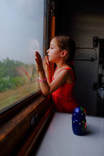 Roztomilá holka ve vlaku. Letní dovolená a pojetí cestování. Dívka ve věku 5 nebo 6 let jezdí vlakem. Dospívající cestují. Holčička s dlouhými vlasy. Dětský portrét - Fotografie, Obrázek