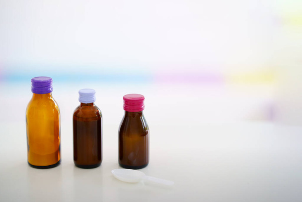 Lasiset lääkepullot värikkäillä korkeilla sumealla taustalla
 - Valokuva, kuva