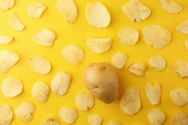 Crispy potato chips snacks with one potato on a yellow background. Image top view, flat lay. - Foto, Imagem
