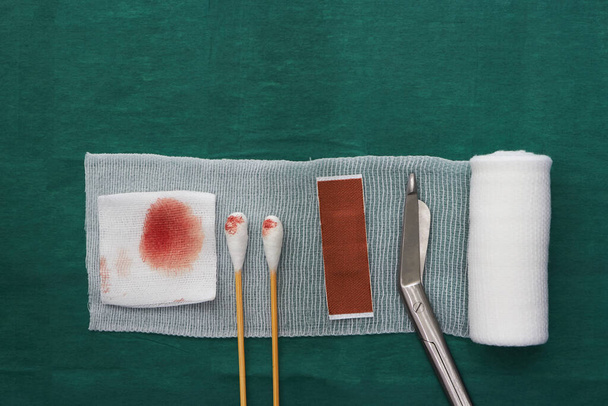 tools includes plaster,swab,blood gauze ,scissors and roll gauze on green surgical dress - Photo, Image