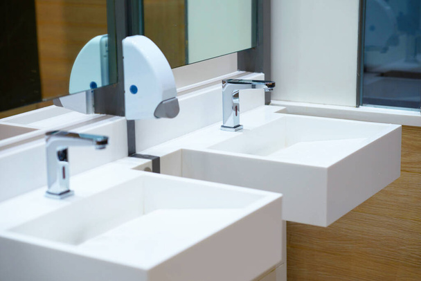 Белая керамическая раковина и кран с мылом в ванной комнате или туалете
 - Фото, изображение