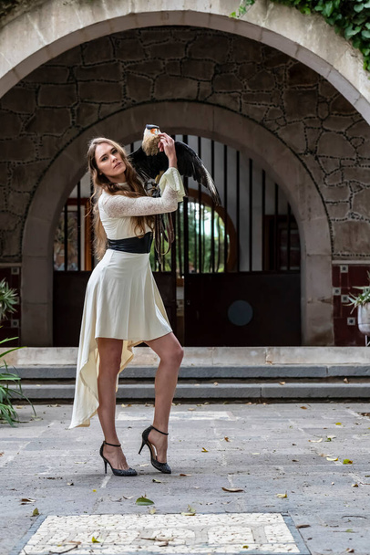 A gorgeous Hispanic Brunette model poses outdoors with a Caracara bird outdoors at a hacienda - Fotografie, Obrázek