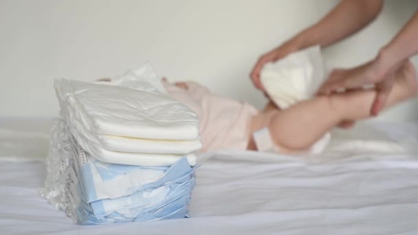 Νεαρή μητέρα αλλάζει το μωρό της άσπρη καθαρή πάνα στο σπίτι στο κρεβάτι - Πλάνα, βίντεο