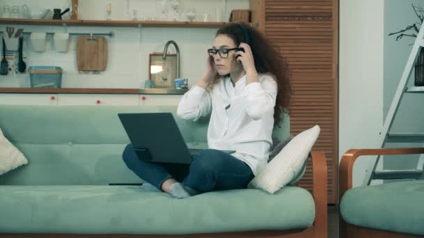 Remote work concept. A woman videocalls via laptop while sitting on a couch during covid19 lockdown. - Materiał filmowy, wideo