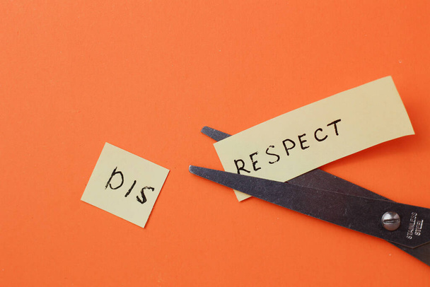 The inscription on the sticker DISRESPECT cut in half on an orange background - Photo, Image