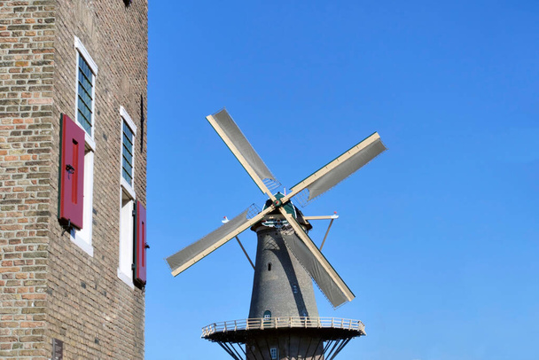 Die Windmühle Molen de Roos in Delft, Niederlande. Die Mühle stammt aus dem 14. Jahrhundert und nahm ihre heutige Form 1760 an. Links die Bagijnetoren aus der Zeit um 1500.                                           - Foto, Bild