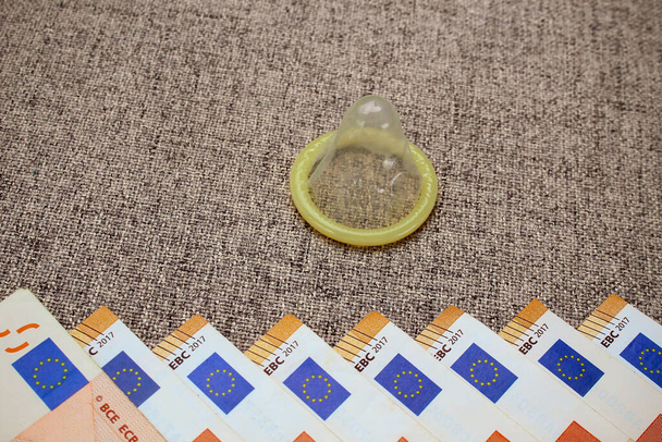Uitgepakt condoom en een heleboel rekeningen van 50 euro op een bank achtergrond, afgezwakt - Foto, afbeelding