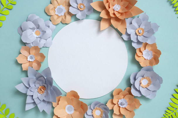Klasik yuvarlak kart çerçeveli düz bir döşeme, mavi arka planda renkli kağıt çiçek tasarımı. Üst görünüm, kopyalama alanı, çiçek sanatı - Fotoğraf, Görsel