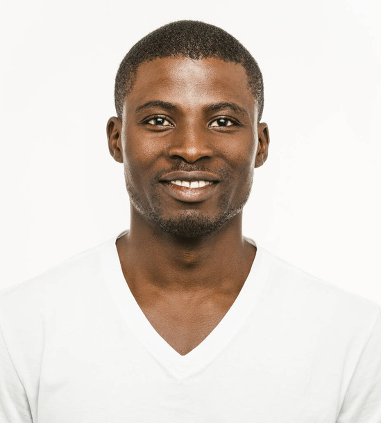 Positive Afro American man Smiles looking at camera. Portrait of dark-skinned cheerful man in white t-shirt isolated on white background. Front view - Fotó, kép