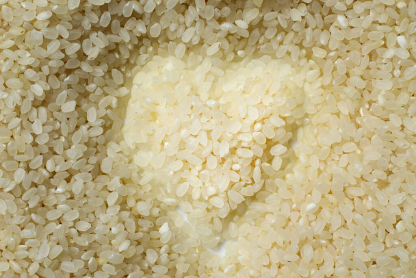 White rice in the shape of a heart, abstract beautiful background - Photo, Image