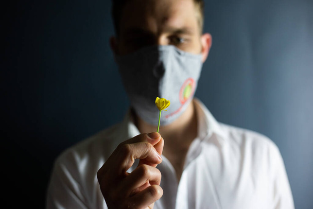 The man in the mask "Stop Coronavirus" sniffs the smell of a fresh flower, COVID-19 - Φωτογραφία, εικόνα