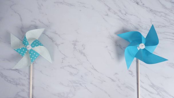 Papel de roda de vento brinquedo real em fundo de pedra de mármore de cor branca que feito de origami feito à mão na cor azul clara material especial japonês e pau de madeira para bebê ou crianças brincando
. - Foto, Imagem