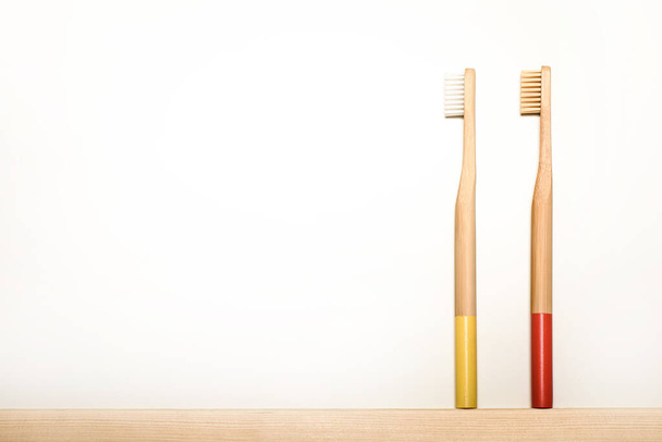 Beyaz arka planda sarı ve kırmızı bambu diş fırçaları. Eko ürün. Çevre dostu. - Fotoğraf, Görsel