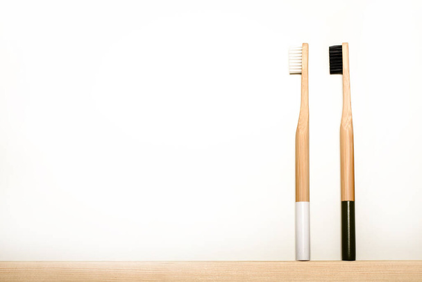 Beyaz arka planda beyaz ve siyah bambu diş fırçaları. Eko ürün. Çevre dostu. - Fotoğraf, Görsel