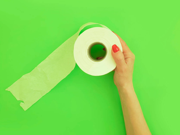 manos femeninas sostienen papel higiénico sobre un fondo de color
 - Foto, Imagen