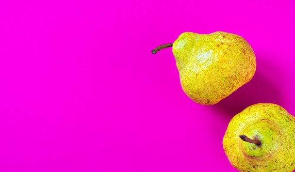 Dos peras frescas, frutas amarillas aisladas sobre papel rosa. Vista superior con espacio de copia
 - Foto, imagen