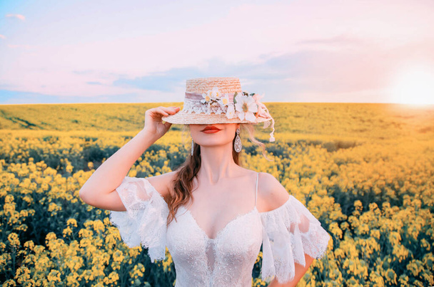portrait retro woman. Lady girl hides her face under retro boater hat. beauty juicy smiling lips. Vintage elegant lace wedding dress. chest medieval corset. Background blooming yellow rapeseed field - Fotoğraf, Görsel