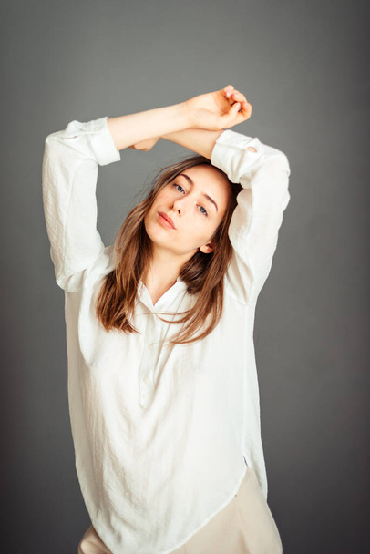 Nuori tyttö valkoisessa paidassa harmaalla taustalla. Ranskalainen nainen valkoisessa puserossa harmaiden seinien taustalla. Koskematta.. - Valokuva, kuva