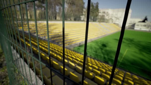 The stadium is fenced with an iron fence. Empty seats in the stadium without spectators and fans. Cancellation of matches due to the coronavirus pandemic, quarantine. Access is closed. - Footage, Video