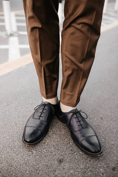 Mans feet image with brown trouser and black leather shoes for fashion magazine outdoor photography concept - Zdjęcie, obraz