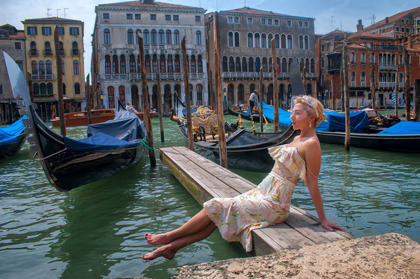 Elegancka kobieta w welonie. Cieszy widok na kanał z przechodzącą gondolą w Wenecji, Włochy - Zdjęcie, obraz