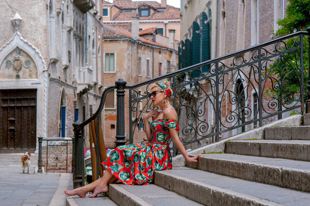 elegante, chica de moda con gafas se sienta en las escaleras del puente, sonriendo, en una Venecia romántica, Italia
 - Foto, Imagen