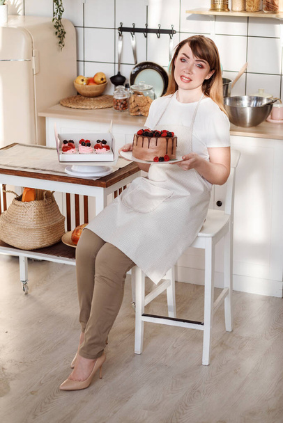 Vertical portrait of nice confectioner woman with cake in her hands.  - Foto, Imagen